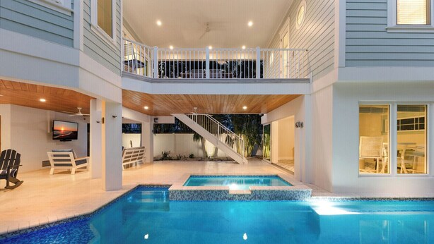 Ein zweistöckiges Haus mit Swimmingpool, Balkon und einer Treppe, die zu der oberen Etage führt.