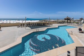 A swimming pool with a spiral design, adjacent lounge chairs, and a beach view. - Phoenix I 1076- Ahhhmazing View! Gulf Front! Best Amenities! 5 Stars! (Orange Beach)