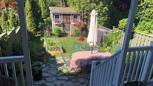 A wooden deck with a table and chairs, a small garden with a shed, and a white fence. - Family home in Saint-Lambert (Saint-Lambert)