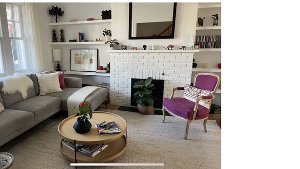A living room with a sofa, armchair, coffee table, fireplace, and shelves with decorative items. - Family home in Saint-Lambert (Saint-Lambert)
