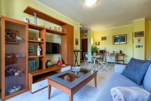 A living room with a sofa, coffee table, wooden shelving, and a TV.