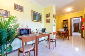 A dining area with a table, chairs, a microwave, and a plant.