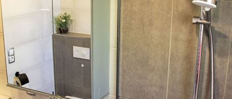 A bathroom with a sink, mirror, shower, and a decorative bird sculpture.