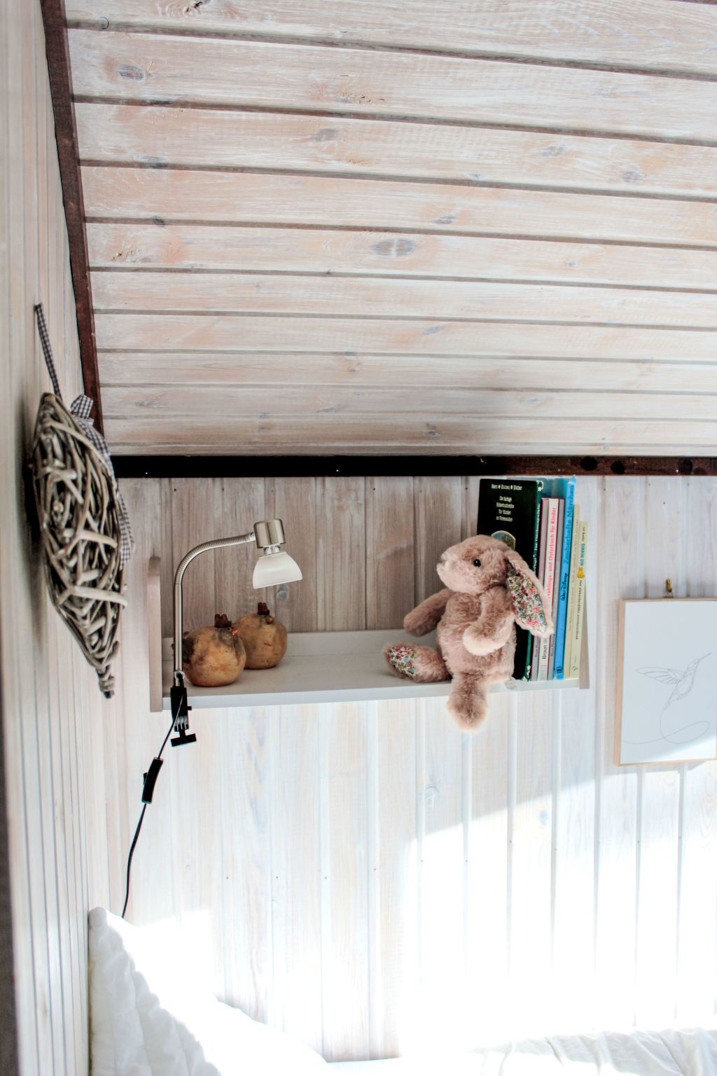 A wooden ceiling with a shelf holding a lamp, a stuffed animal, and books.
