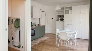 A modern kitchen with a dining area, wooden flooring, and white cabinetry. - Lambrate Design District - Apartment a stone's throw from the subway (Milano)