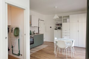 Eine moderne Küche mit Essbereich, Holzboden und weißen Schränken.