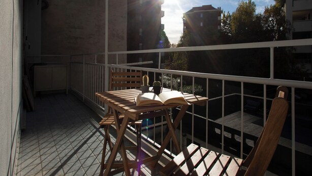A balcony with a wooden table, a chair, and an open book. - Lambrate Design District - Apartment a stone's throw from the subway (Milano)