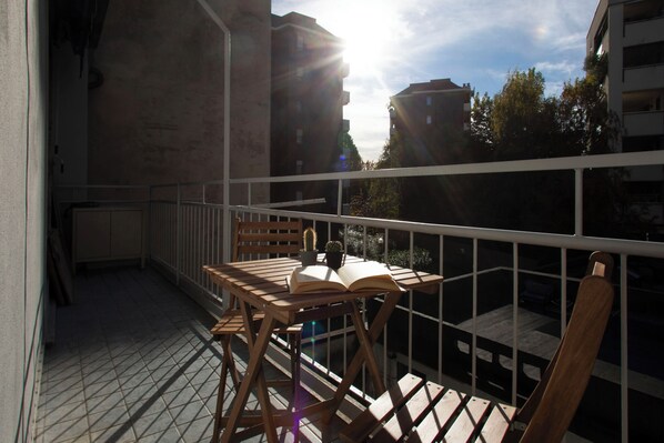 Ein Balkon mit Holztisch, einem Stuhl und einem offenen Buch.