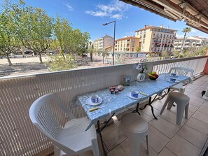 Ein Balkon mit Tisch und Stühlen für zwei Personen, Blick auf die Straße und Gebäude im Hintergrund.
