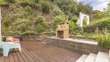 Una terraza de madera con asientos incorporados, una chimenea de ladrillo y un muro de contención de piedra.