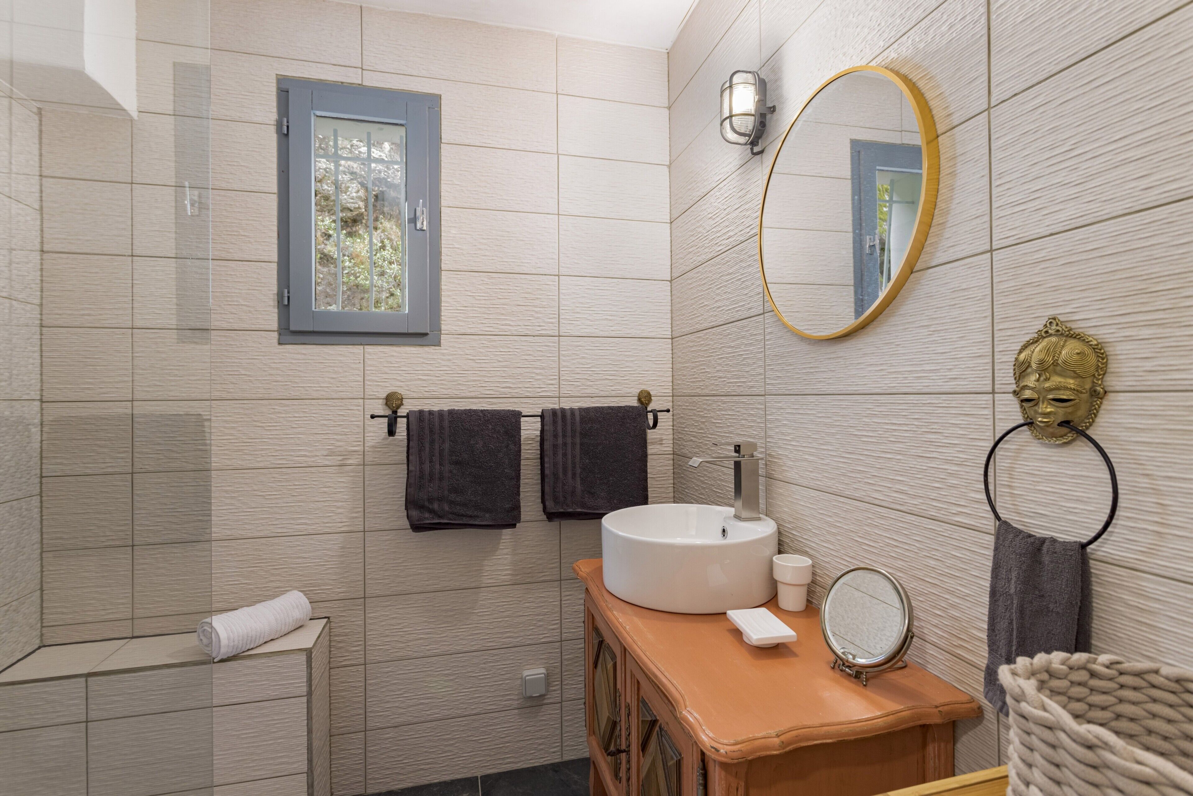 A bathroom with a window, a sink with a mirror, and towels.