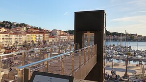 Un paysage urbain côtier avec un port de plaisance, des bâtiments historiques et une plateforme d’observation moderne.