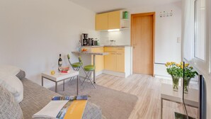 Ein kompakter Wohnraum mit Küchenzeile, Essbereich und einer Sitzecke mit Sofa und Couchtisch.