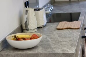 A kitchen counter with a bowl of fruit, a kettle, and a toaster.