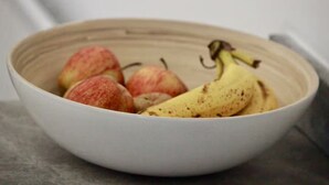 Un bol con una banana y duraznos.