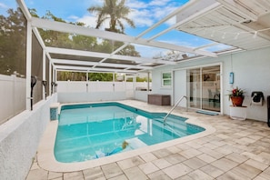 A covered swimming pool with a glass door leading to a patio area. - Mermaid Dreams - Perfect Location Close to Everything! (Bradenton)