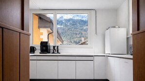 Une cuisine de taille réduite avec une fenêtre donnant sur un paysage montagneux boisé.