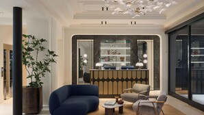 Ein modernes Interieur mit einer Rezeption, einer Sitzecke und einer großen Pflanze in einem Topf.