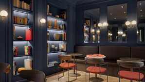 Ein modernes Interieur mit dunkelblauen Wänden, Bücherregalen und runden Tischen mit Hockern.