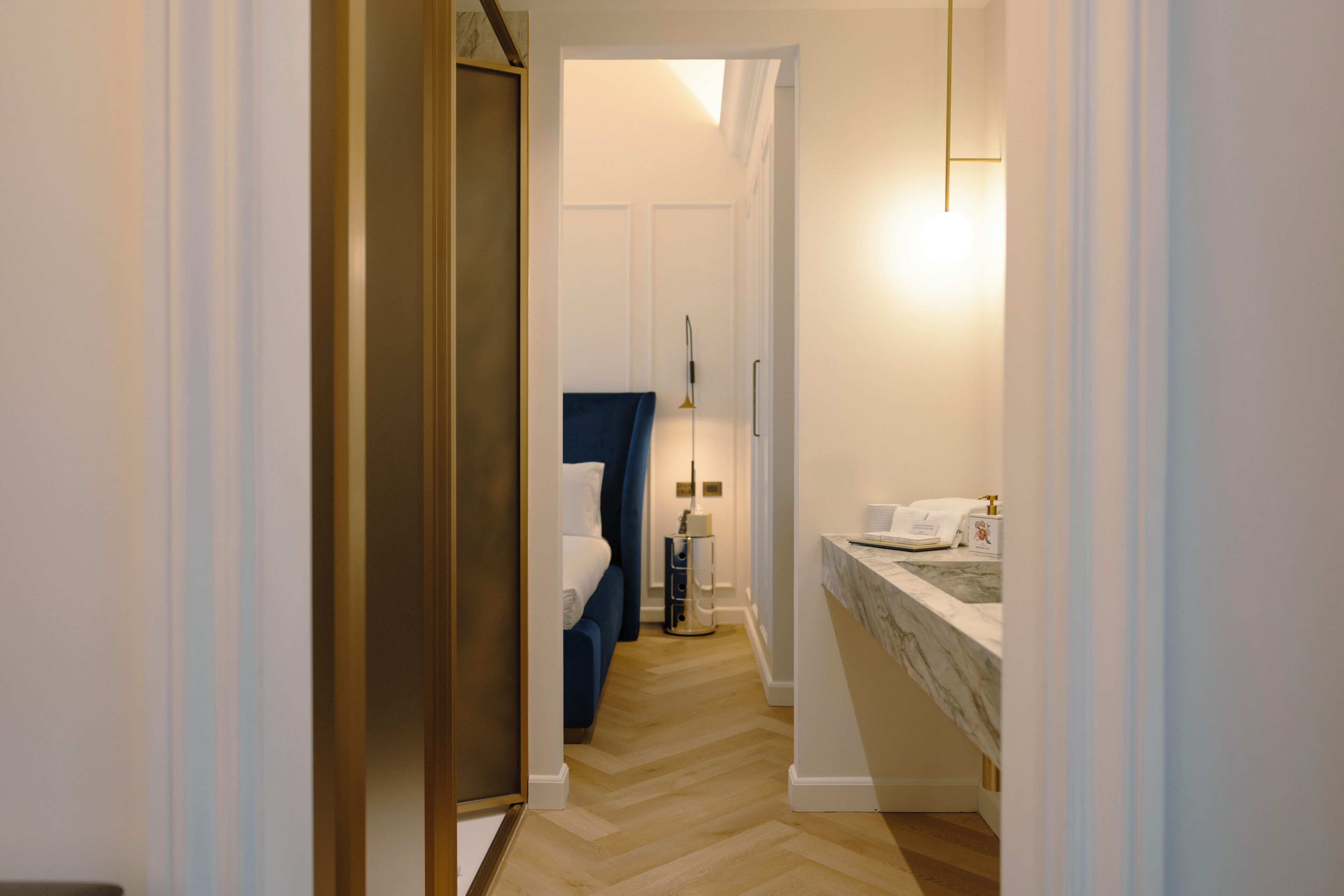 Un couloir étroit mène à une chambre à coucher qui contient un lit, une table de chevet et une commode.