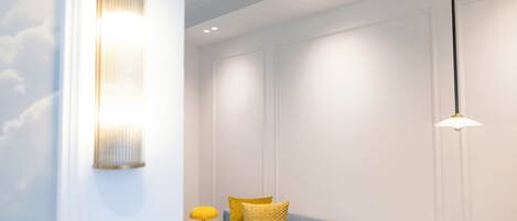 A room with a blue sofa, a yellow lamp, and a wall-mounted light fixture.