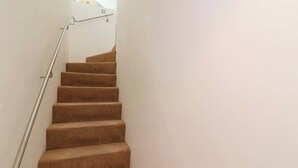 A staircase with carpeted steps and a metal handrail. - 12 Nautilus (Bideford)