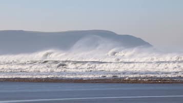 A beach with waves crashing onto the shore and a distant mountain.