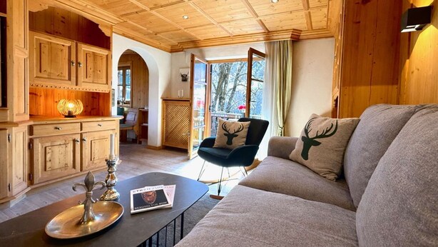 A cozy living room with a sofa, a coffee table, and wooden cabinets. - KitzSpirit by Belle-Stay (Kitzbühel)