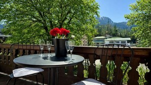 A round table with a metal base, two chairs, a metal railing, and a view of a mountain and buildings. - KitzSpirit by Belle-Stay (Kitzbühel)