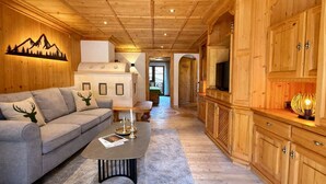 A cozy living room with a sofa, coffee table, and wooden cabinets. - KitzSpirit by Belle-Stay (Kitzbühel)