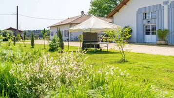 Une maison à l’extérieur blanc, avec une porte bleue et une tente blanche dans la cour.