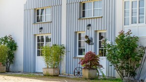 A building with a corrugated metal exterior, multiple windows, and potted plants in front.