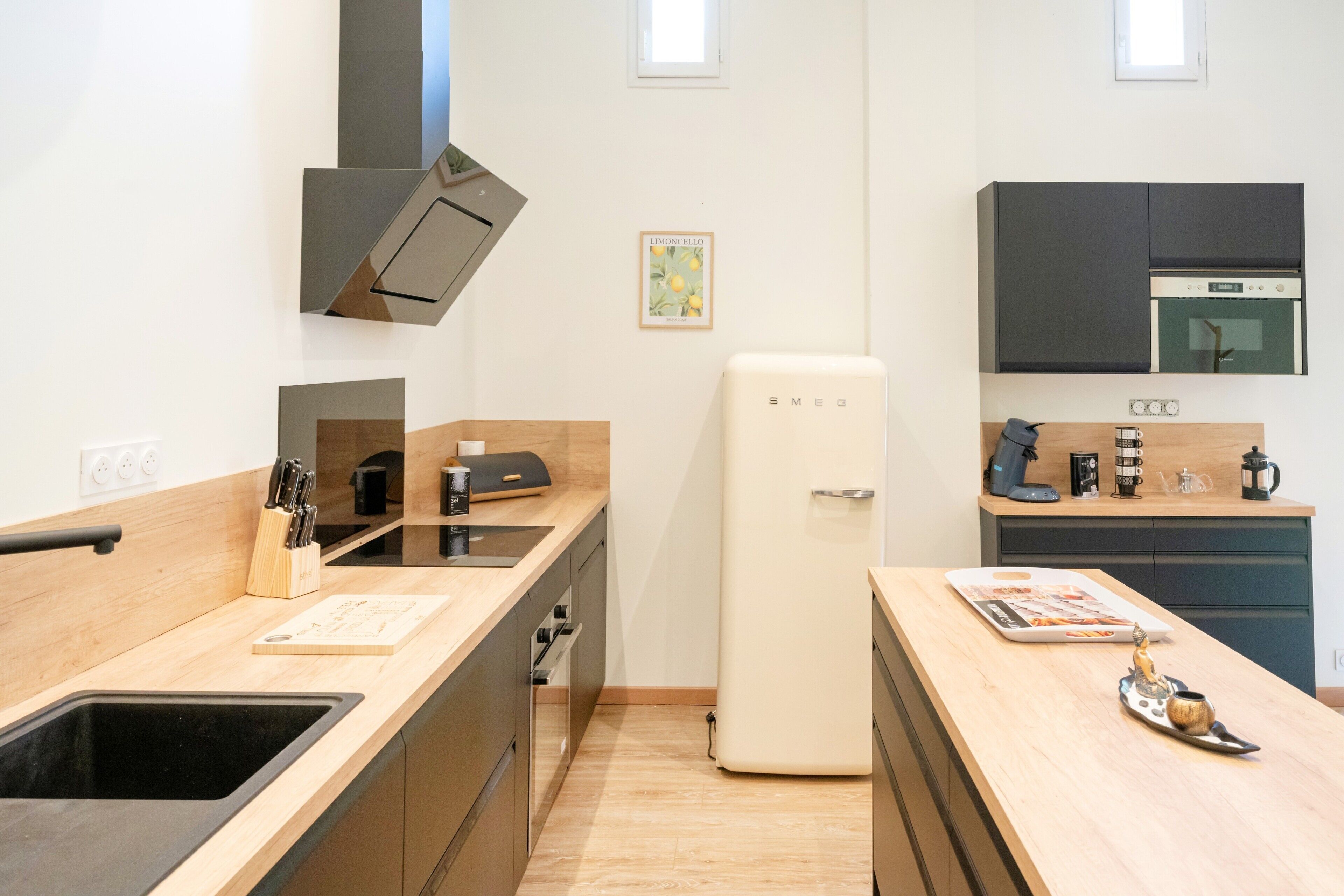 A modern kitchen with a black sink, wooden countertop, and a white refrigerator.