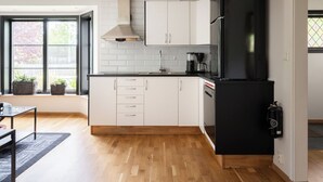 A modern kitchen with white cabinets, a black refrigerator, a coffee maker, and a window with a view of trees. - Mellebyrundan by Interhome (Mellbystrand)