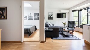 A modern living room with a sofa, coffee table, and TV. There is a bed with a view in the background. - Mellebyrundan by Interhome (Mellbystrand)