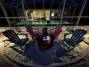 A fire pit with chairs around it, a pool, and a house in the background. - Salted Sunset at Punta Gorda Isles (Punta Gorda)