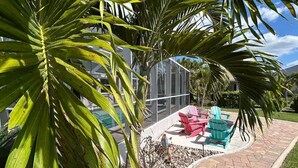 Eine Terrasse mit Glasveranda, Sitzgelegenheiten im Freien und einem Pool.
