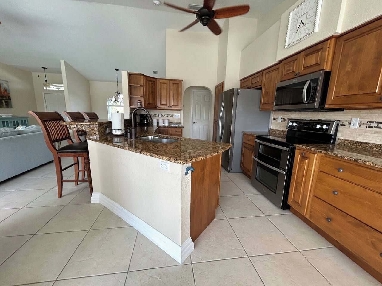 A kitchen with a central island, wooden cabinets, stainless steel appliances, and a ceiling fan.