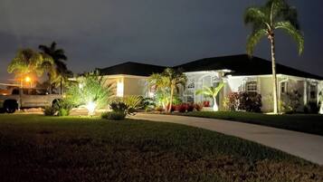 A residential house with a driveway, palm trees, and a vehicle parked outside.