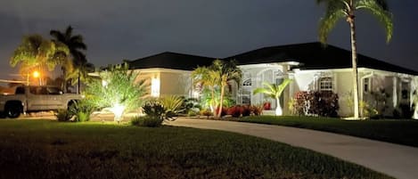 A residential house with a driveway, palm trees, and a vehicle parked outside.