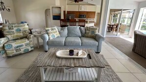 Ein Wohnzimmer mit einer Couch, einem Couchtisch und einer Küche im Hintergrund.