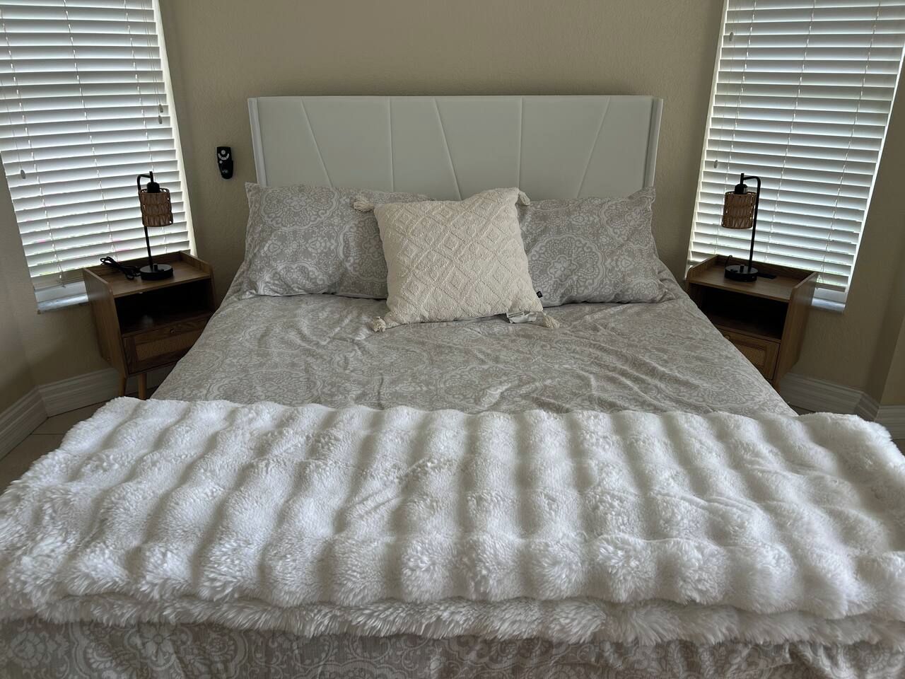 A bed with a white headboard, two bedside tables with lamps, and a patterned bedspread.
