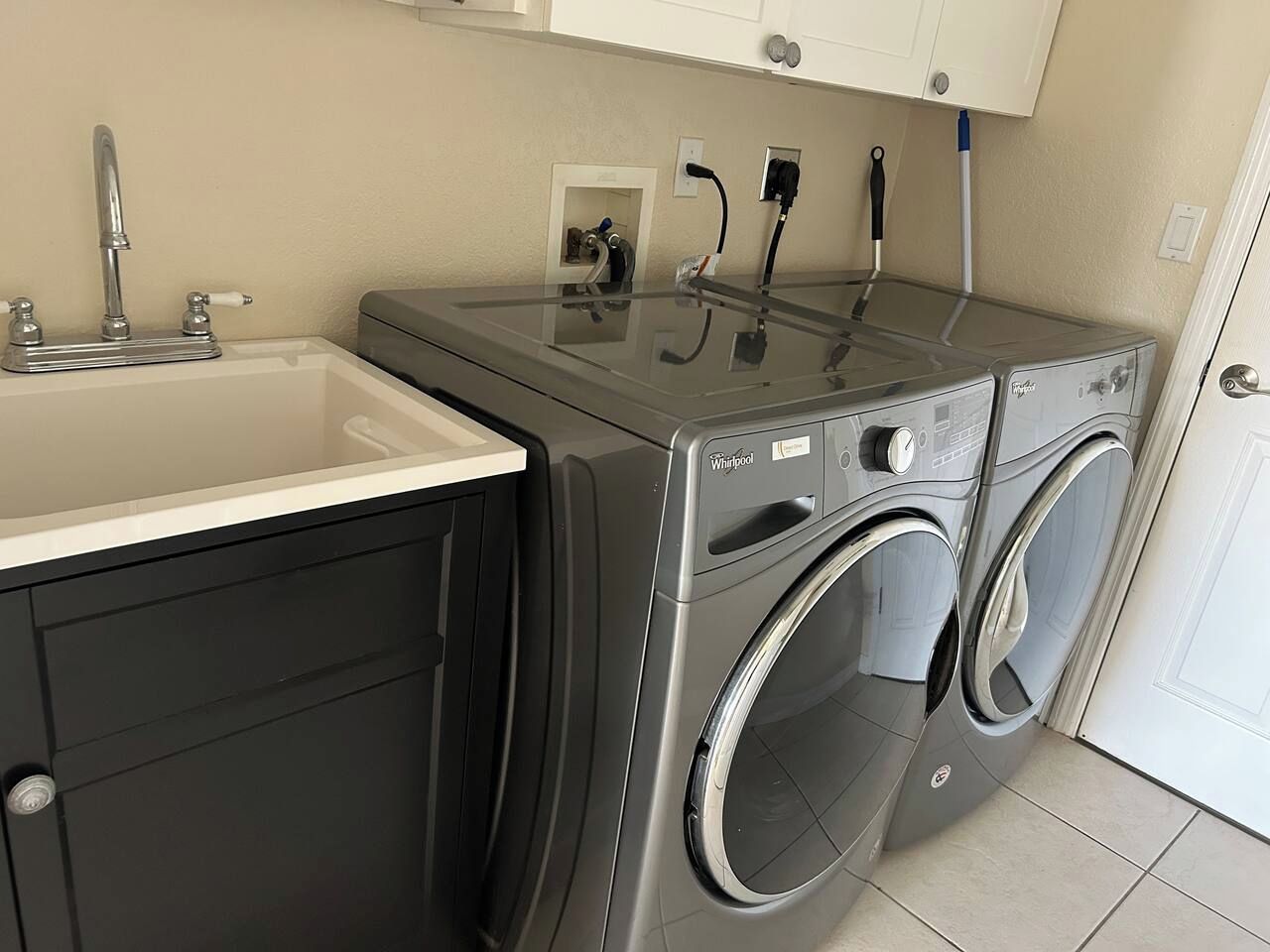 A compact laundry area with a washing machine and dryer, a sink, and a cabinet.