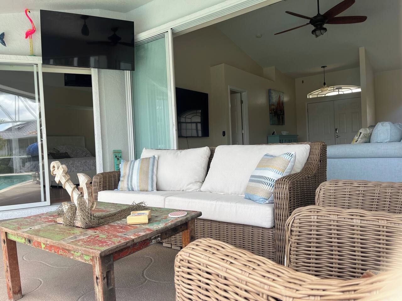 A room with a white sofa, wicker furniture, a coffee table with decorative items, and a ceiling fan.