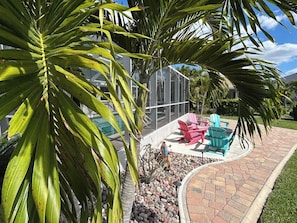Eine Terrasse mit Sitzgelegenheit und einem Pool im Hintergrund.