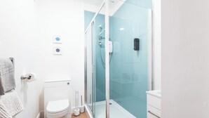 Une salle de bain moderne équipée de toilettes, d’une douche et d’un porte-serviettes.