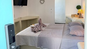Ein Schlafzimmer mit einem Bett, einem Fernseher, einem Spiegel, einem Nachttisch und einer Hängelampe.