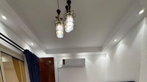 Un dormitorio con cama, aire acondicionado, puerta corrediza de vidrio y una araña.