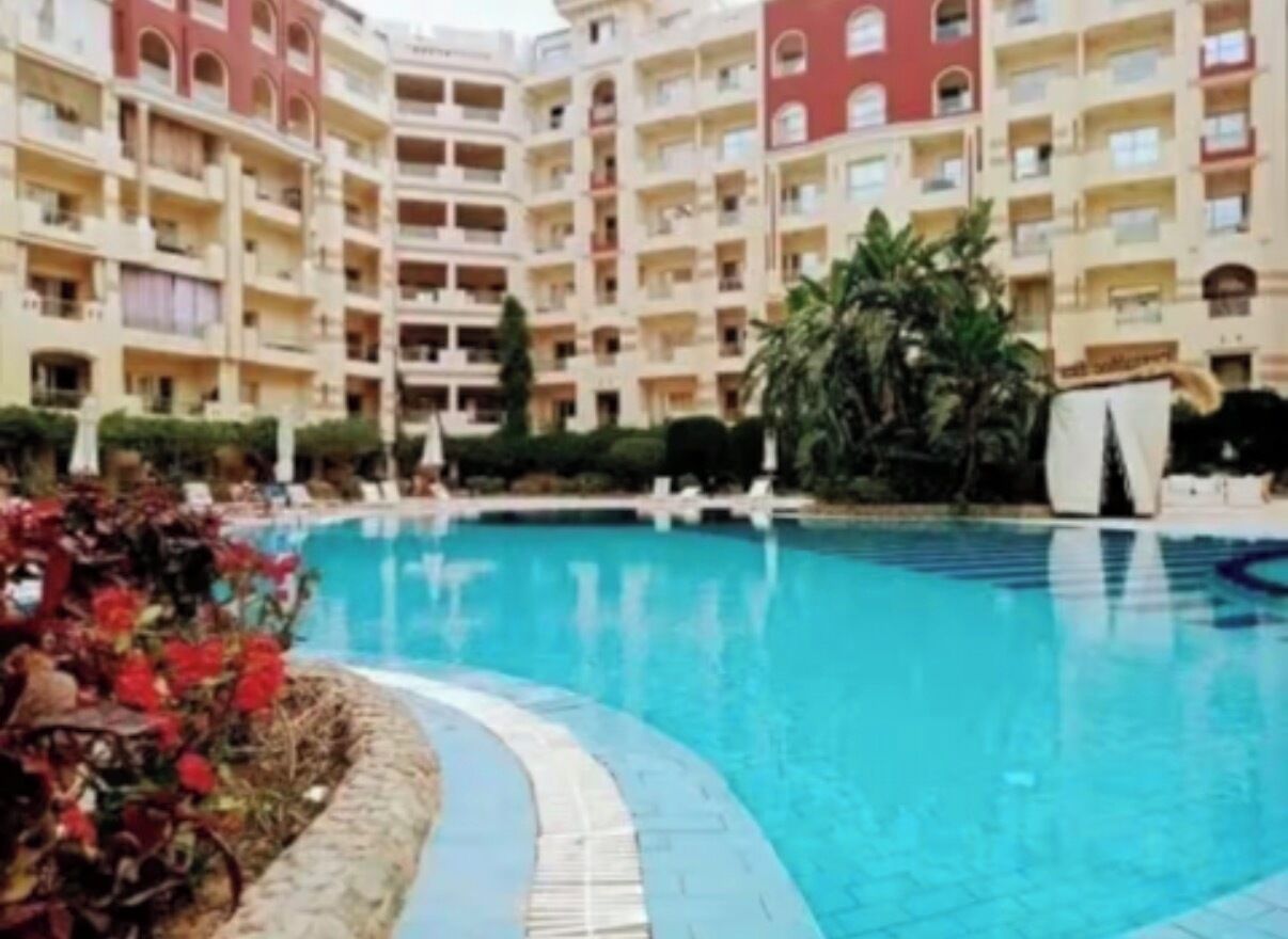 A swimming pool surrounded by a multi-story building with balconies.