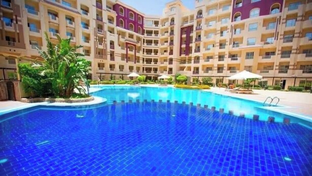 Un hotel con una amplia piscina cubierta, varios balcones y un patio central.